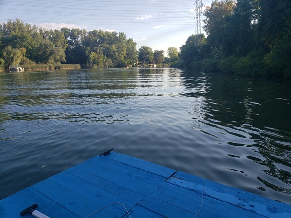 A view of the Erie canal with a sliver of the boat's deck in frame towards the bottom
